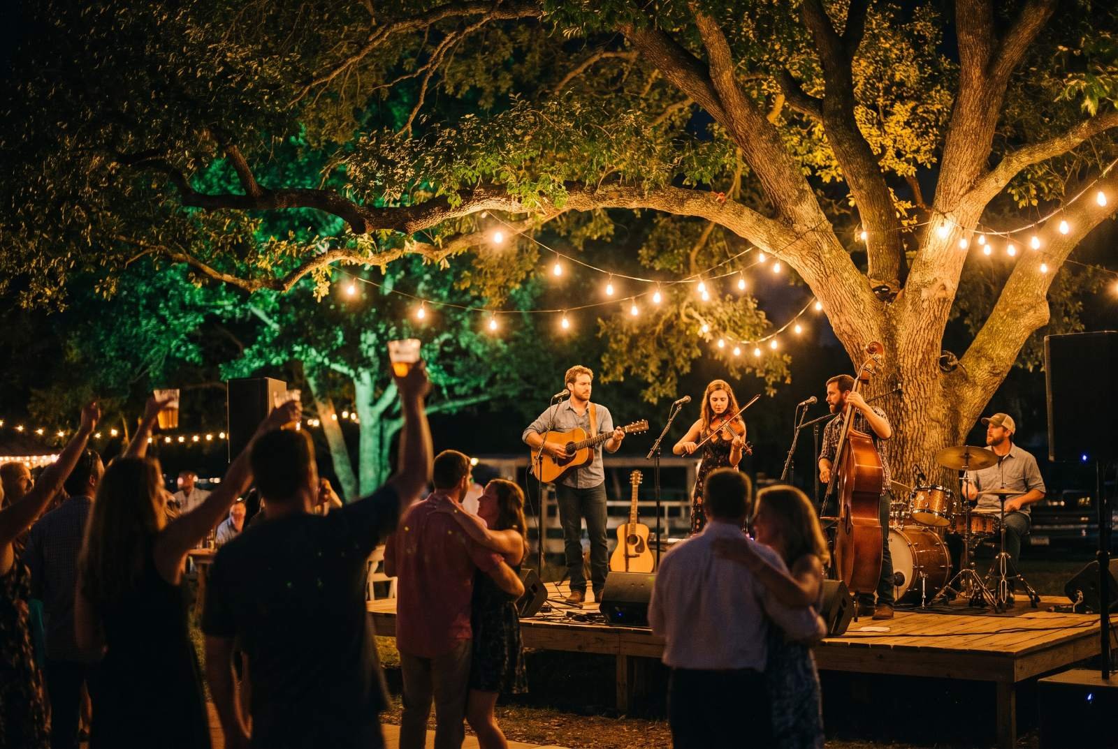 A band playing on the patio stage under string lights at night